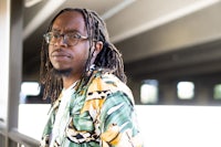 a man with dreadlocks is leaning against a railing