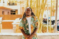 a man in a hawaiian shirt standing in front of bamboo